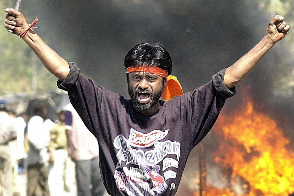 Indian Bajranj Dal activist armed with a iron stick shouts slogans against Muslims as material burns in Gujurat state in February 2002. Photo: AFP/File