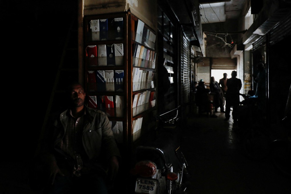 A man sits outside his shop during a country-wide power breakdown in Karachi, Pakistan. Photo: Reuters