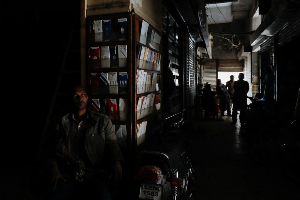 A man sits outside his shop during a country-wide power breakdown in Karachi, Pakistan. Photo: Reuters