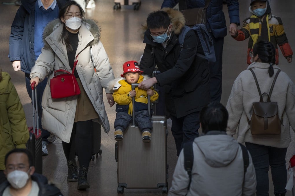 A man pushes a child riding on a suitcase at Beijing West Railway Station, Jan. 18, 2023. A declining population will pose new challenges for China’s leaders. Photo: AP