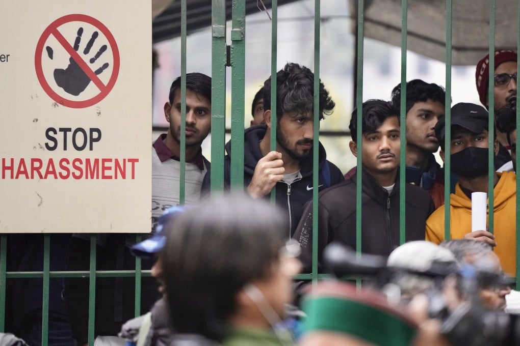 Students watch security personnel guard a gate of Jamia Millia Islamia university in New Delhi on Wednesday. Tensions escalated after a student group said it planned to screen a banned BBC documentary that examines Prime Minister Narendra Modi’s role during 2002 riots. Photo: AP
