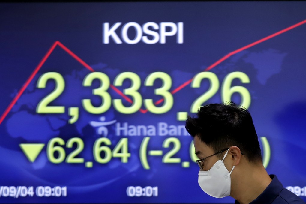 A currency trader walks by a screen showing the Korea Composite Stock Price Index (KOSPI). Photo: AP/File