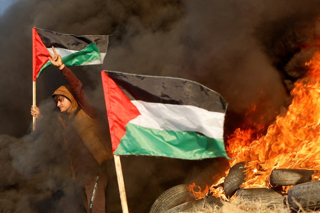 A man holds a Palestinian flag during clashes with Israeli forces, near the Israel-Gaza border east of Gaza City on Thursday. Photo: Reuters