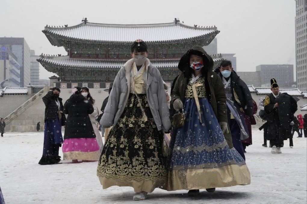 Women wearing traditional Korean attire walk in the snow at the Gyeongbok Palace in Seoul on Thursday. Photo: AP