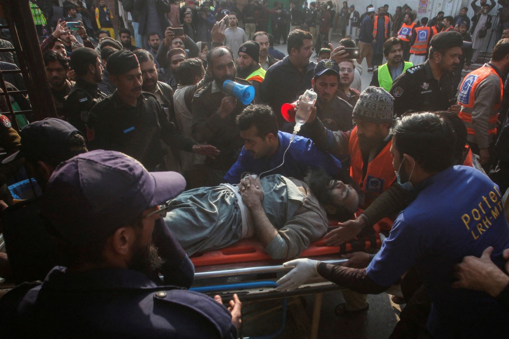 Men move an injured victim after a suicide blast in a mosque in Peshawar on Monday. Photo: Reuters