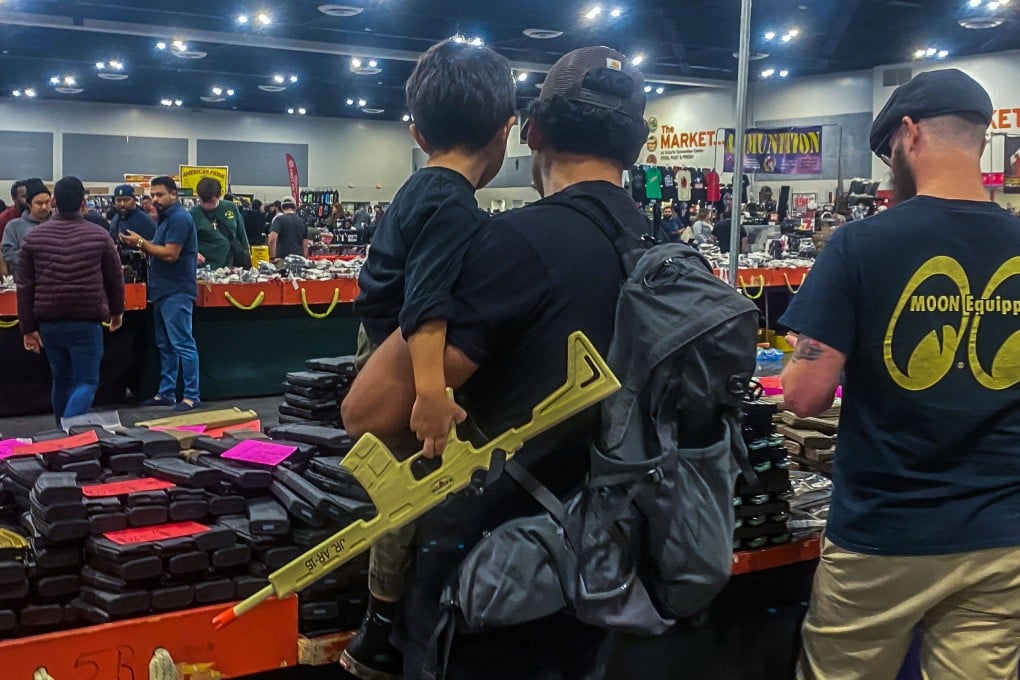 A man and his son holding an AR15 toy gun browse at the Crossroads of the West Gun Show. Photo: AFP