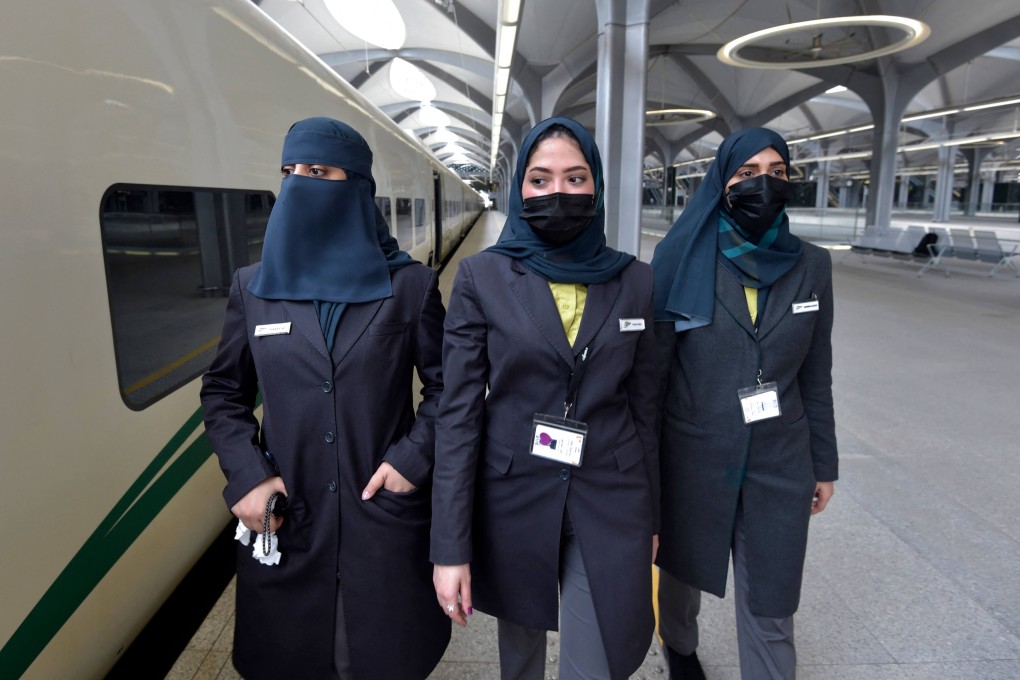 Saudi conductors walk beside a high-speed train ferrying pilgrims to Mecca. Photo: AFP