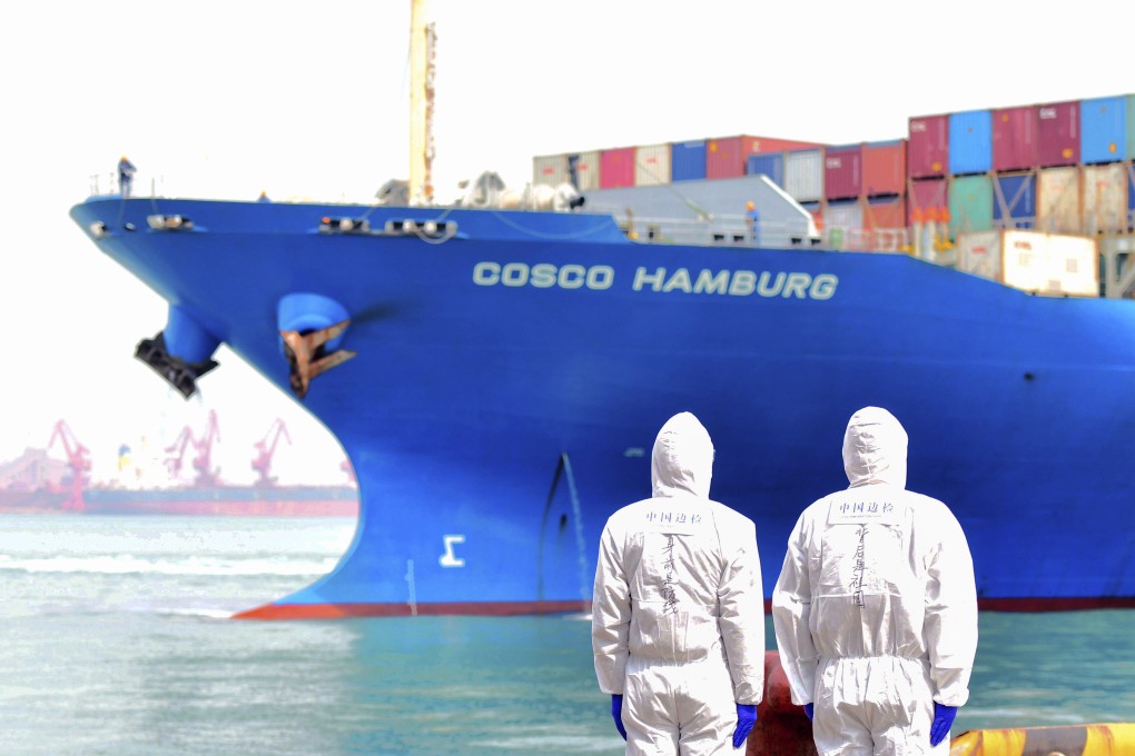 Workers in protective suits stand near a container ship docked at a port in Qingdao in China’s Shandong Province in March 2020. Photo: Chinatopix via AP