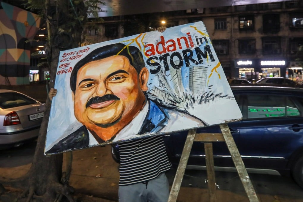 An Indian artist carries a painting of billionaire industrialist Gautam Adani, chairman of Adani Group, in Mumbai last week. Photo: EPA-EFE