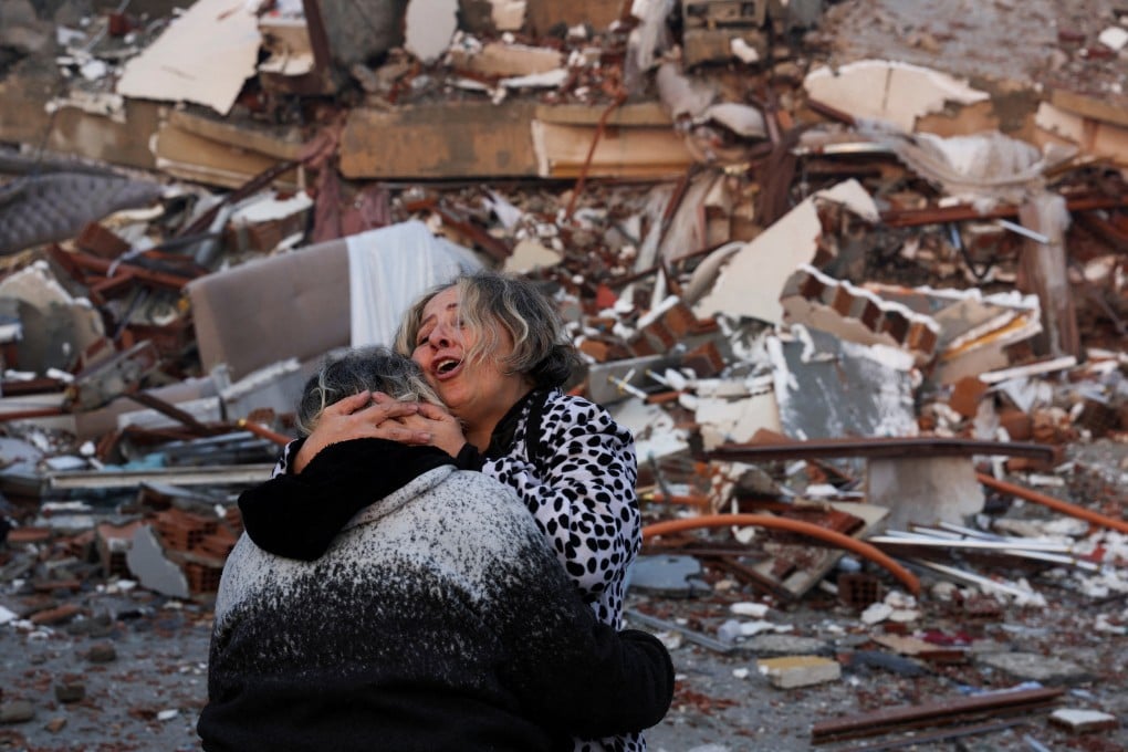 A woman embraces another person near rubble in Hatay, Turkey. Photo: Reuters