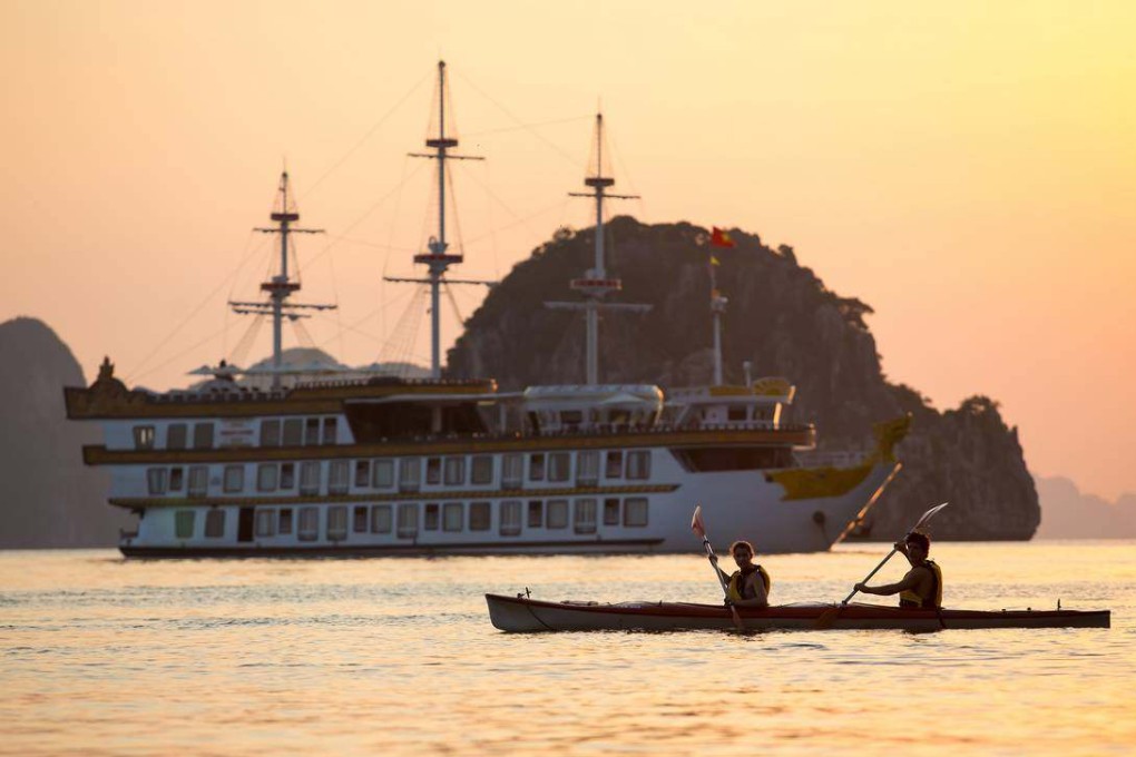 Kayakers paddle past the Dragon Legend cruise ship in Halong Bay, Vietnam. Photo: Indochina Junk
