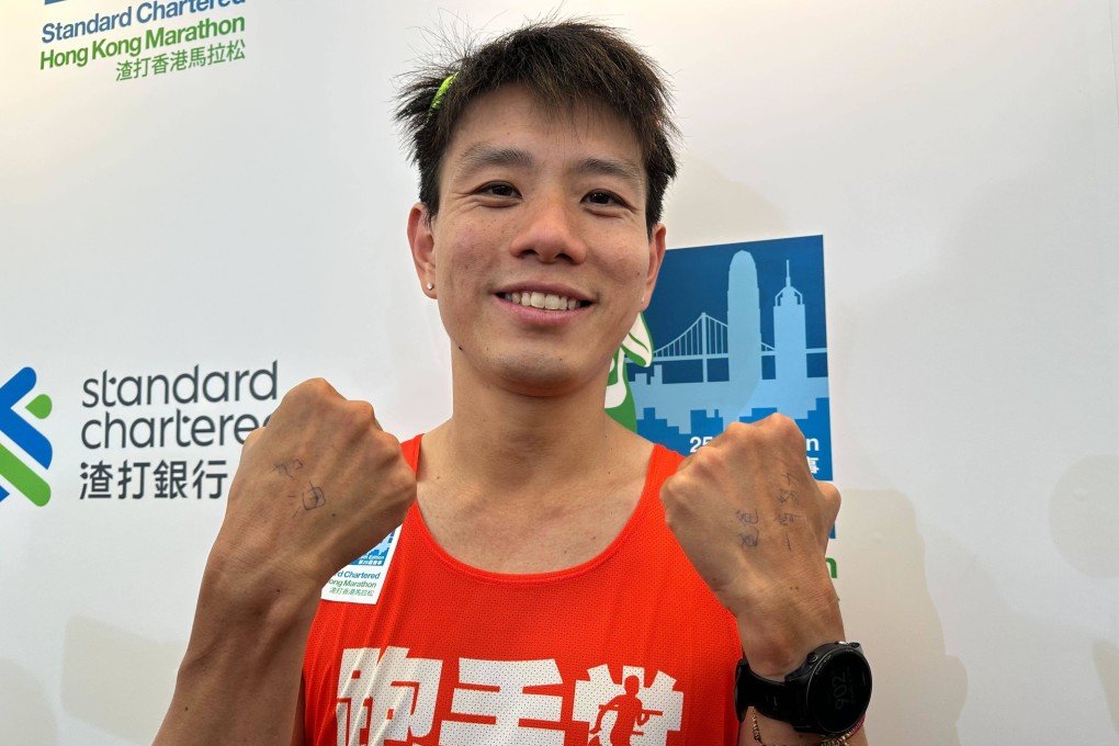 Gi Ka-man displays a message for his father on his hands after finishing as the fastest local runner in the Hong Kong Marathon.