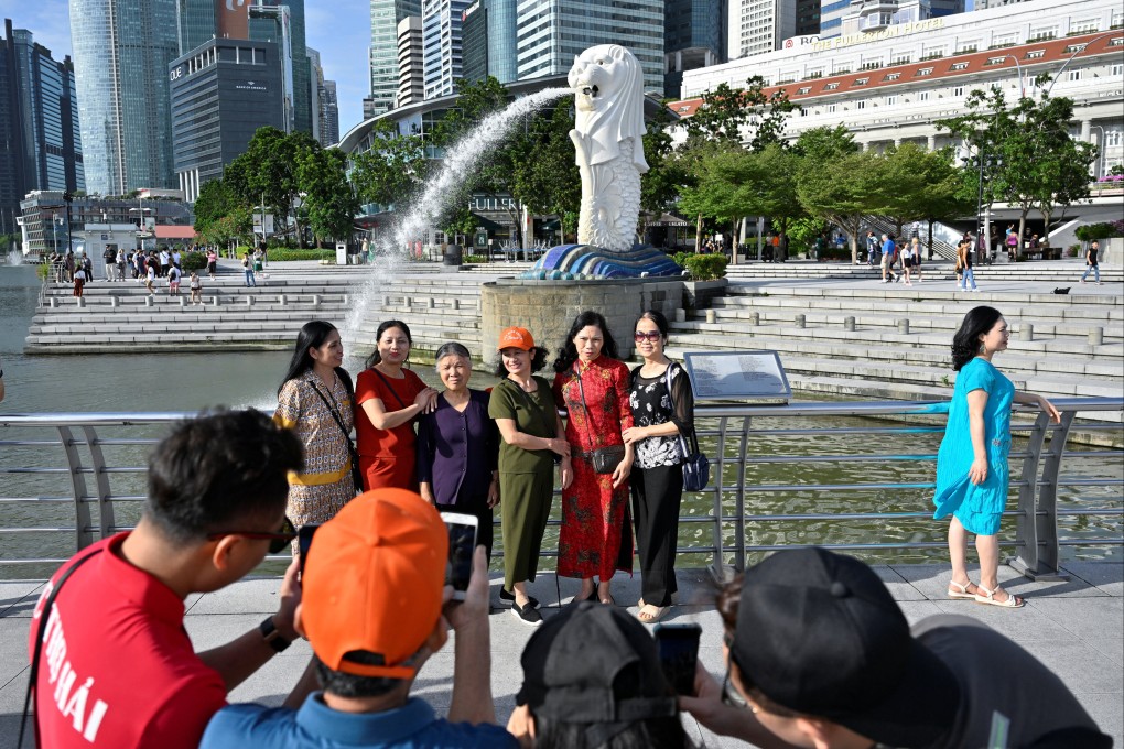 Tourists pose for photographs at the Merlion Park in Singapore. Photo: Reuters