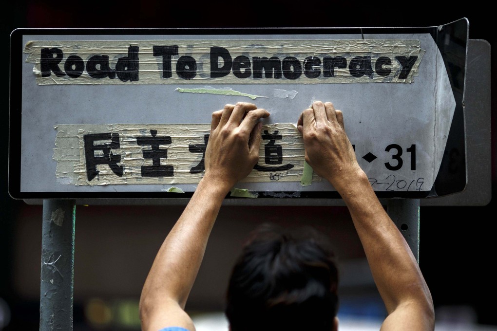 A worker removes masking tape left on a  road sign by pro-democracy protesters during a clearance at the last “Occupy” protest site blocking a main road in Causeway Bay on December 15, 2014. Photo: Reuters