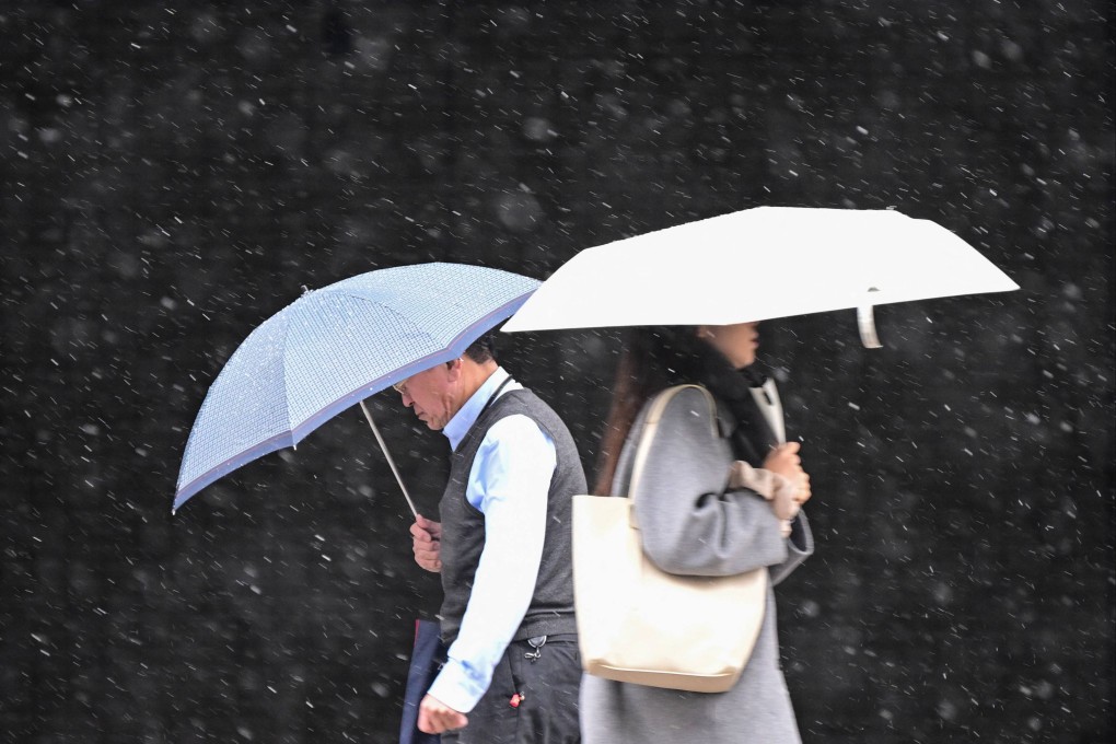 People walk on a street in Koto district as it snows in Tokyo on February 10. Since 2020, Japan’s economy has been hit by Covid-19, while the war in Ukraine has driven up prices globally and in Japan. Photo: AFP