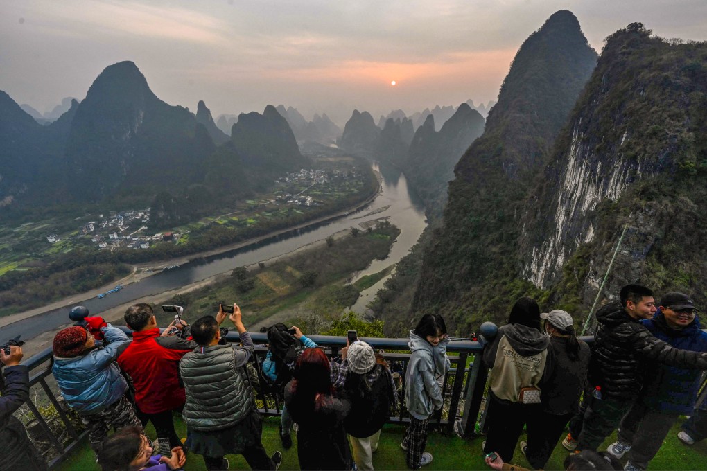 Chinese tourists watch a sunrise on the west bank of the Li River in Yangzhou, Guangxi province, on Tuesday. Photo: AFP