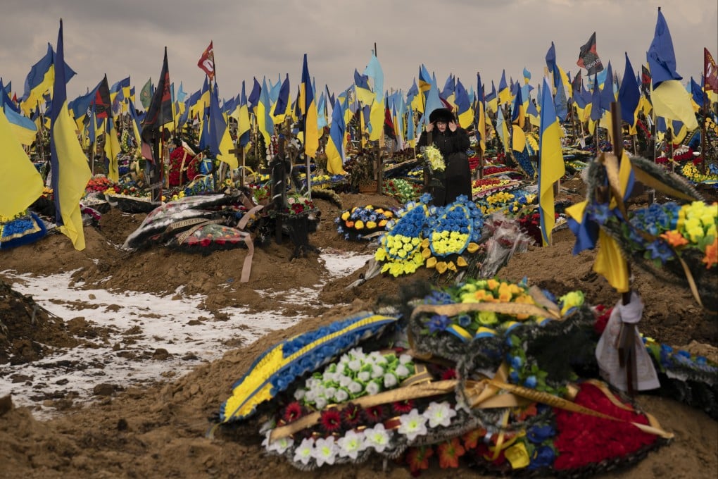 A woman walks between the graves of soldiers, in Kharkiv, Ukraine. Russia pummeled Ukraine with a barrage of missiles on Thursday as the war’s one-year anniversary neared. Photo: AP