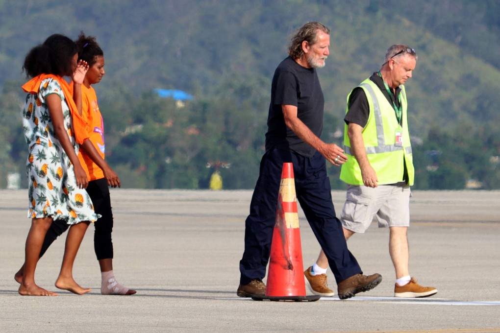 Australian Bryce Barker (2nd R), held for a week in Papua New Guinea by an armed group, is escorted from a plane following his release on Sunday. Photo: AFP