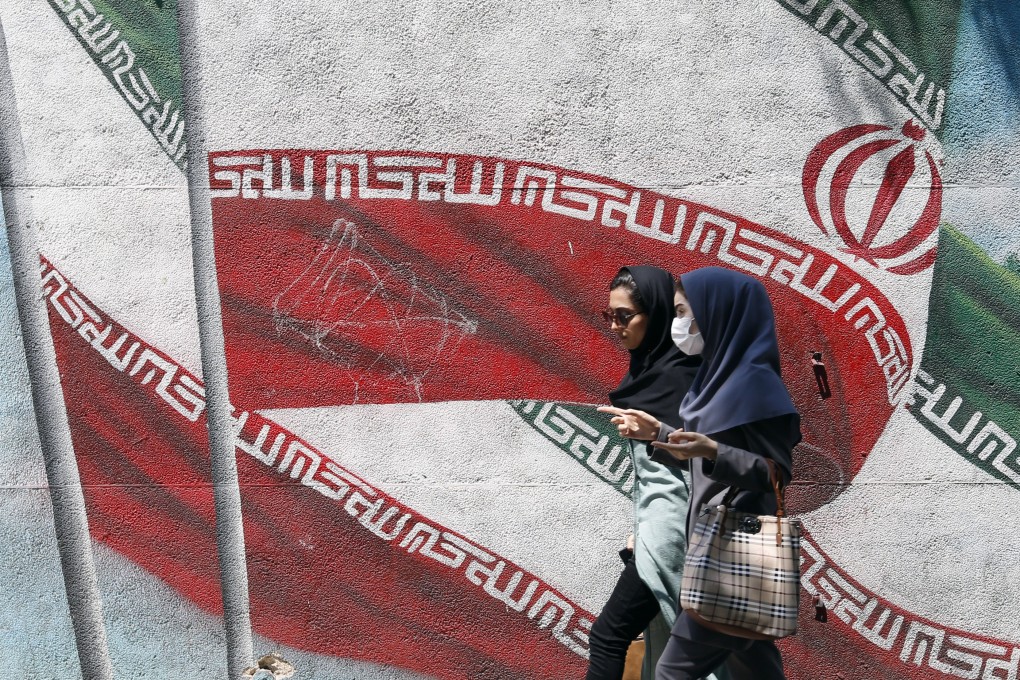 Young Iranians walk past a painting of Iran’s national flag in a street in Tehran. There are reports some schoolgirls are being poisoned to prevent them learning. File photo: EPA-EFE