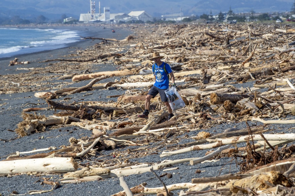 A resident walks among the debris washed ashore in Napier, New Zealand from Cyclone Gabrielle, on February 19, 2023. Photo: NZ Herald via AP
