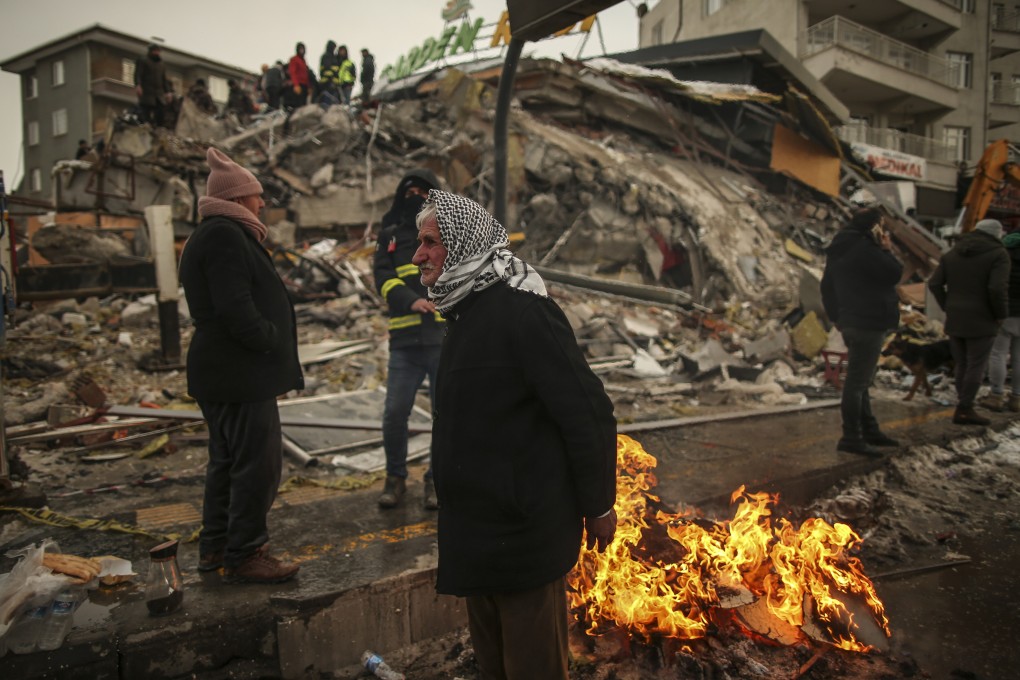 People warm themselves next to a collapsed building in Malatya, Turkey. A magnitude 5.6 earthquake shook Turkey on Monday, three weeks after a catastrophic quake killed thousands. File photo: AP