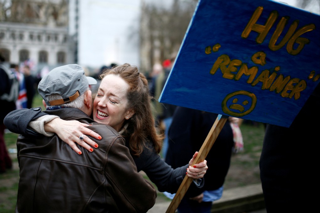 An anti-Brexit protester hugs a man while holding a placard on Brexit day in London, Britain, on January 31, 2020. Photo: Reuters