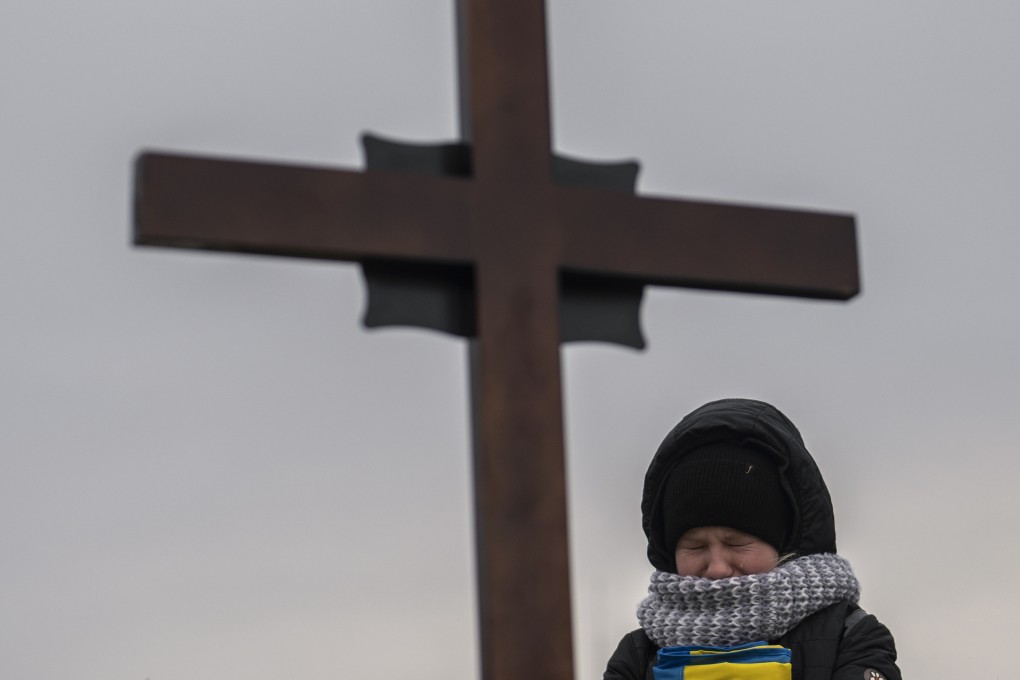 Sophia, holding a Ukrainian flag, cries above the grave of her father, a soldier, during a funeral at Lviv cemetery, western Ukraine. Photo: AP