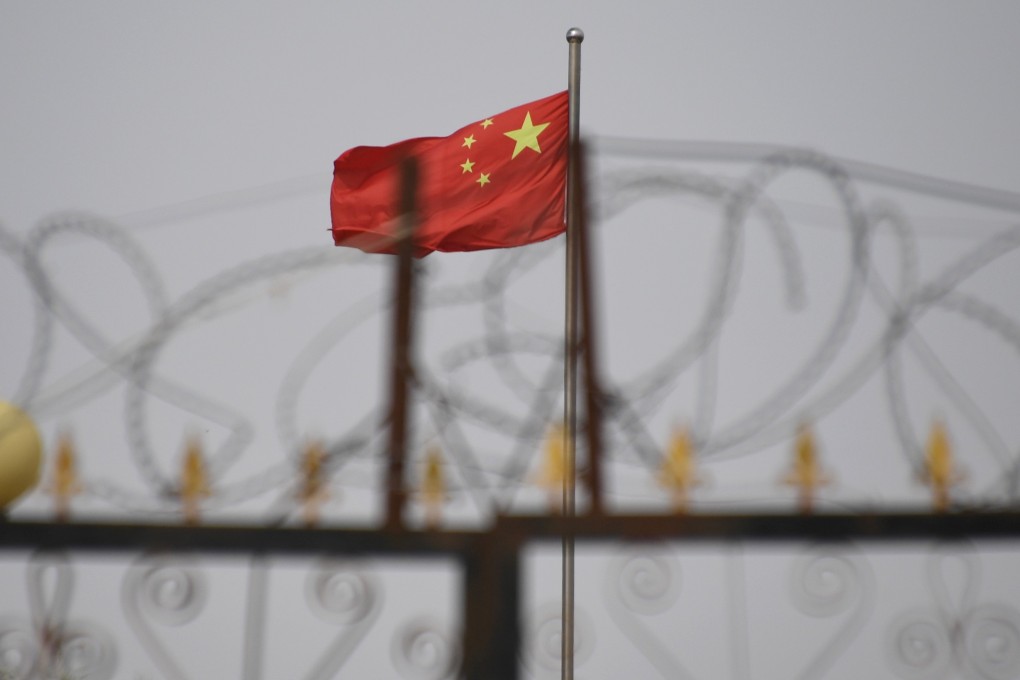 A Chinese flag flutters behind barbed wire at a housing compound in Yangisar, south of Kashgar in Xinjiang. Photo: AFP
