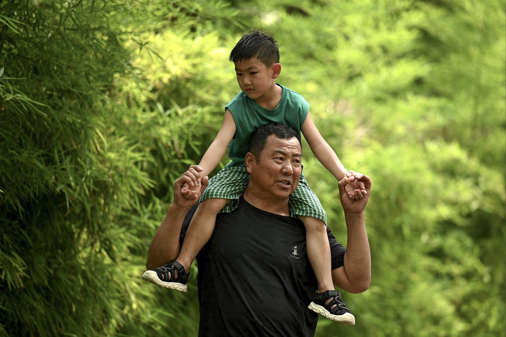 A man carries a child on his shoulders along a street in Beijing on August 2, 2022. Falling births is accelerating population ageing in China, a problem it has grappling with for years. Photo: AFP