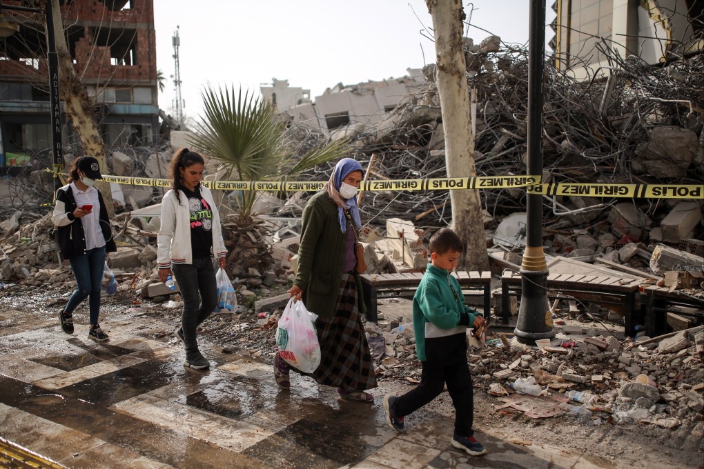 People walk in front of collapsed buildings in the aftermath of powerful earthquakes in Adiyaman, Turkey, in February. Photo: EPA-EFE