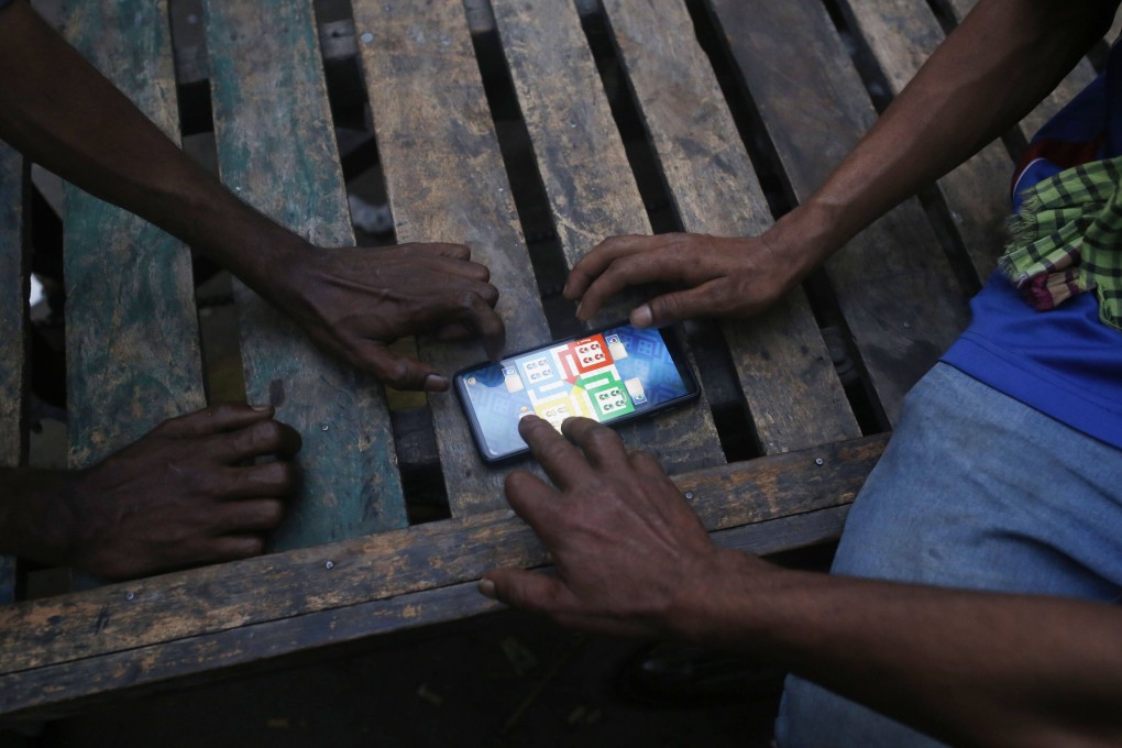 Bangladeshi labourers gather around a smartphone to play Ludo. Photo: Rehman Asad