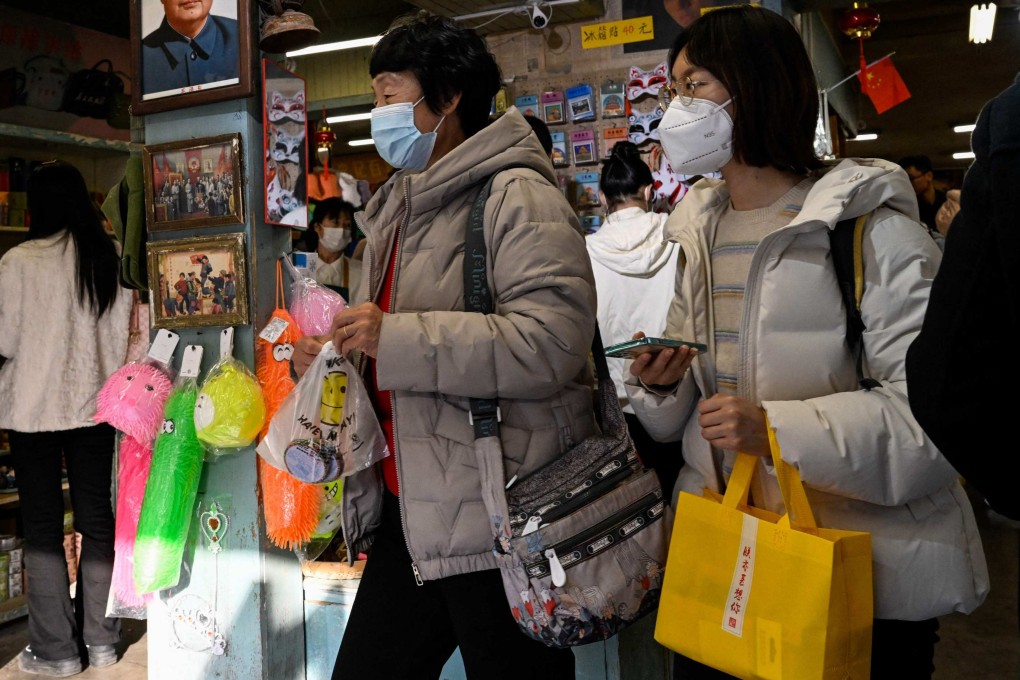 People shop at a store with a picture of the late communist leader Mao Zedong on the wall at the Nanluoguxiang alley in Beijing. With the reopening of China after the ending of Covid-19 restrictions, a new confidence seems to be surging through the country. Photo: AFP