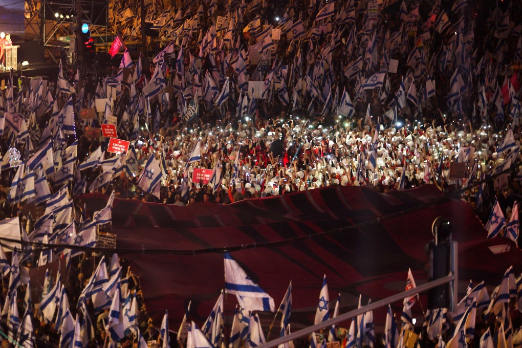 Demonstrators lift national flags during a protest against the Israeli government’s controversial judicial reform bill in Tel Aviv on Saturday. Photo: AFP