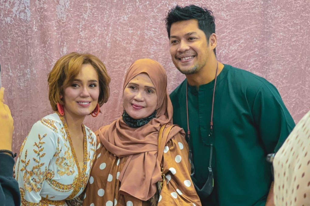 Malaysian actor Kamal Adli (right) and his wife Uqasha Senrose (left) take pictures with a fan at a Hari Raya Mega Sale 2023 event at Singapore Expo on Sunday. Photo: Instagram/@kamaladli