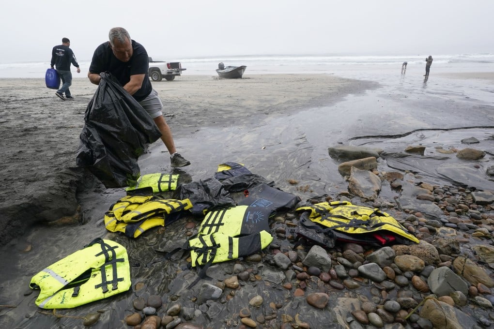 A boat salvager picks up life preservers in front of one of two boats sitting on Blacks Beach in San Diego, California, US on Sunday. Photo: AP
