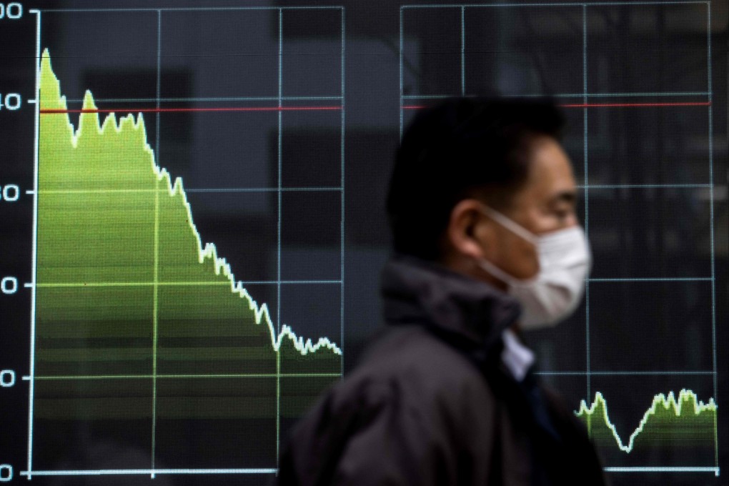 A pedestrian walks past an electronic quotation board displaying a graph of the Tokyo Stock Exchange’s Nikkei 225 index. The Nikkei share average was down more than 2 per cent on Tuesday. Photo: AFP