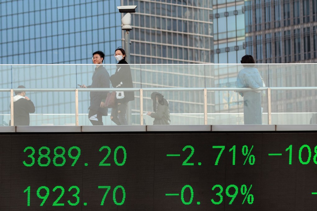 People cross the pedestrian bridge with a screen showing the latest stock exchange data in the Lujiazui financial district of Shanghai. Photo: EPA-EFE