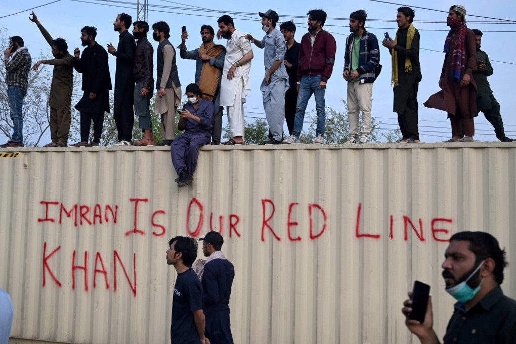 Supporters of Pakistan former Prime Minister Imran Khan stand atop shipping containers that were placed for security reasons outside a court, in Islamabad. Photo: AFP