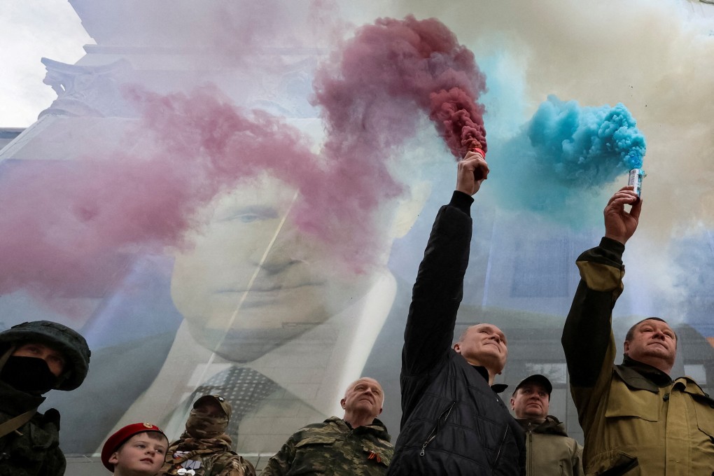 Participants burn flares in front of a banner with a portrait of Russian President Vladimir Putin during a patriotic flash mob marking the ninth anniversary of Russia’s annexation of Crimea. Photo: Reuters