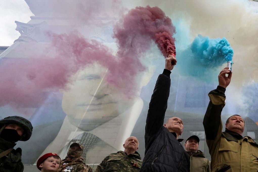 Participants burn flares in front of a banner with a portrait of Russian President Vladimir Putin during a patriotic flash mob marking the ninth anniversary of Russia’s annexation of Crimea. Photo: Reuters