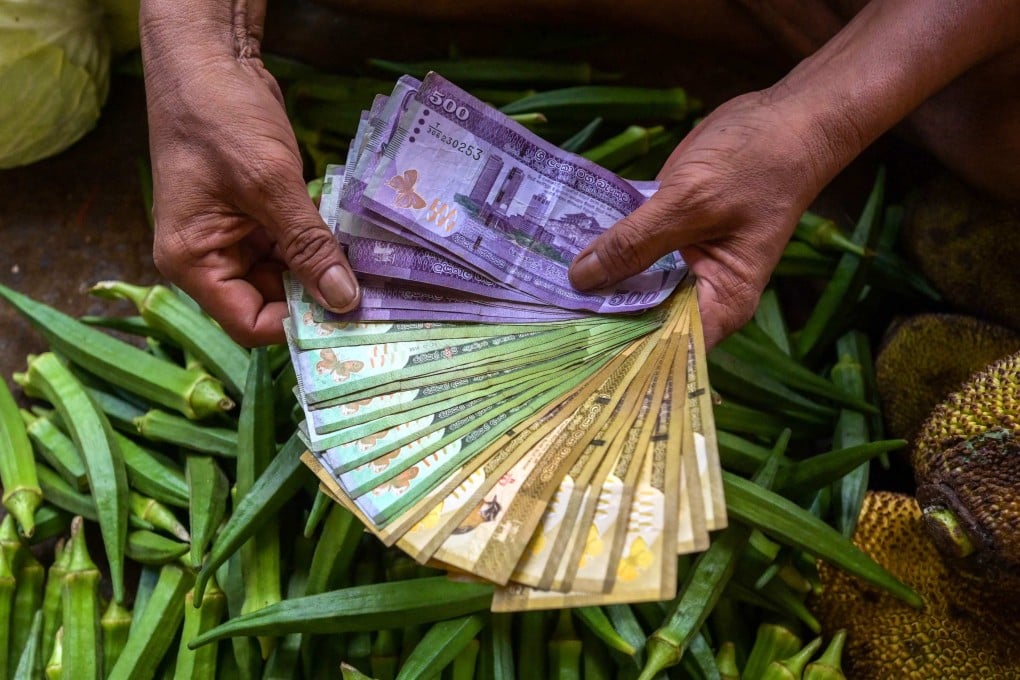 A vegetable seller holds Sri Lankan bank notes while working at a market in Colombo on Monday. The nation is grappling with soaring prices, supply shortages and eroded foreign-currency reserves since defaulting on its overseas debt last year. Photo: AFP