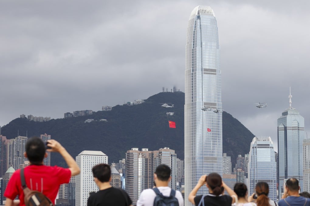 People in Tsim Sha Tsui watch Government Flying Service helicopters carrying the national and Hong Kong special administrative region flags during a flag-raising ceremony at Golden Bauhinia Square in Wan Chai to celebrate the 25th anniversary of the establishment of the Hong Kong special administrative region on July 1, 2022. Photo: Nora Tam