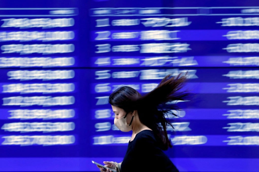 A woman walks past an electric monitor displaying recent stock price movements outside a bank in Tokyo on March 22. Since SVB plunged into crisis, Japan’s Topix Banks Index has lost 15 per cent. Photo: Reuters