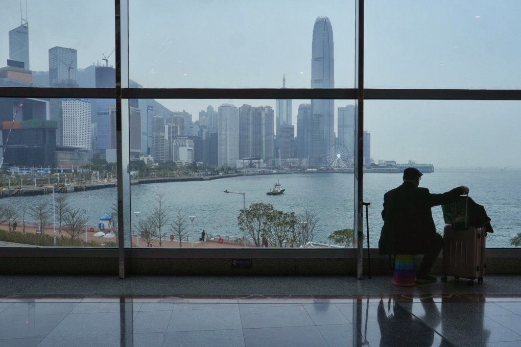 A man with luggage sits on his own portable stool inside the Hong Kong Convention and Exhibition Centre, as clouds roll in over Victoria Harbour. Photo: Elson Li