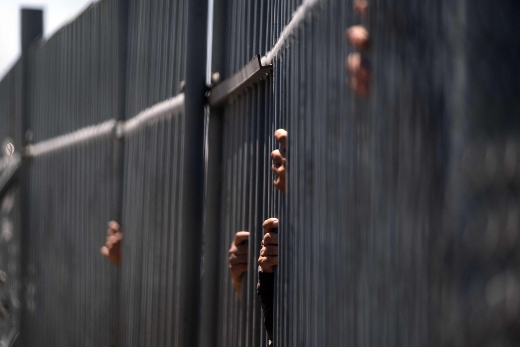 Migrants hold the fence bars of the immigration detention center where 39 migrants died during a fire in Ciudad Juarez, Mexico. Photo: AFP