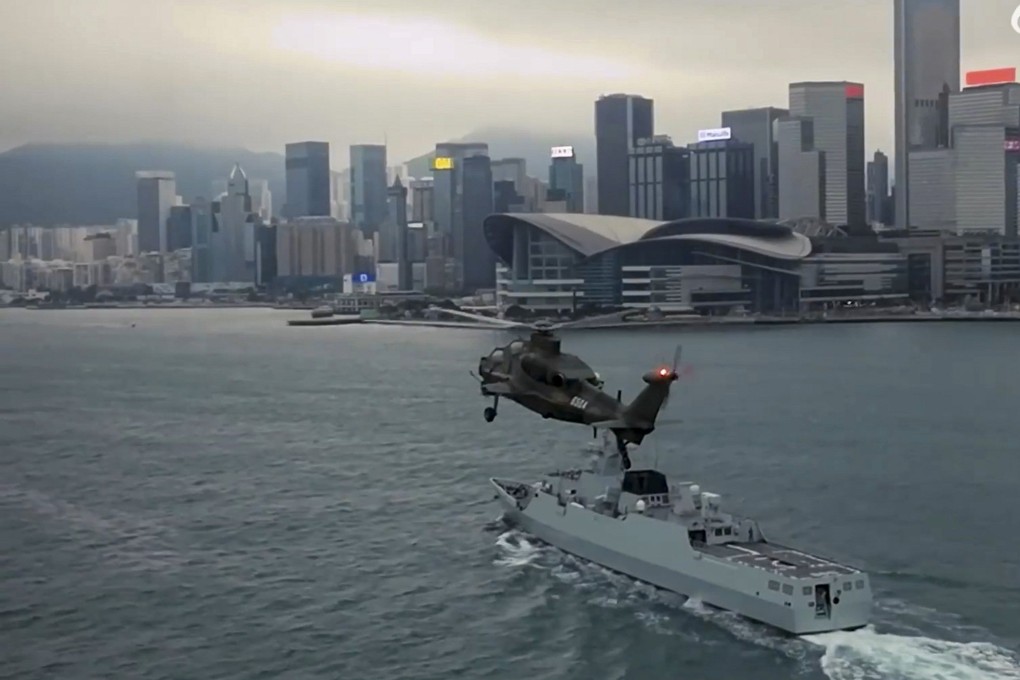 A helicopter and warship pass in front of the Hong Kong Exhibition and Convention Centre. Photo: Weibo