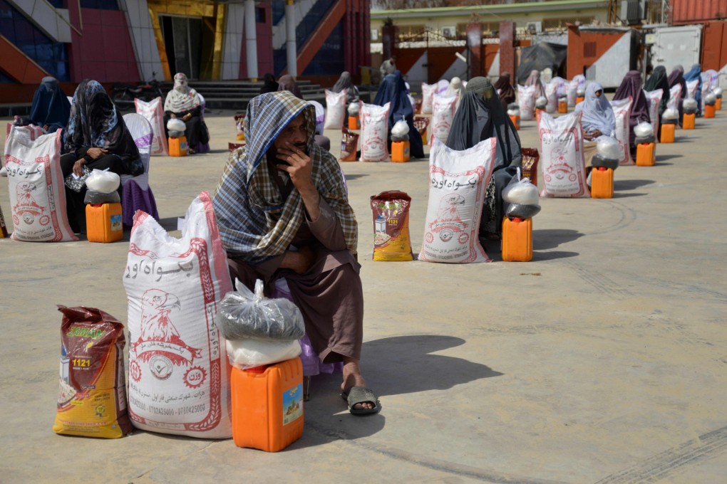 Afghans sit next to food aid distributed by a charity in Kandahar on March 28. Photo: AFP