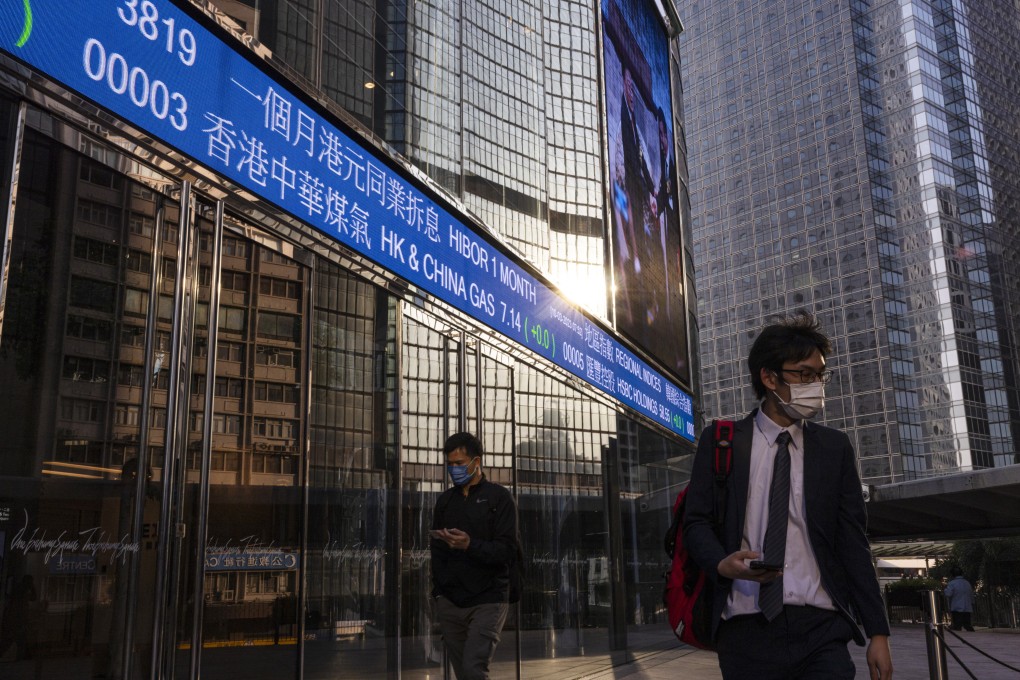 People walk past a screen displaying stock data at Exchange Square in Hong Kong on March 10, 2023. Photo: AP