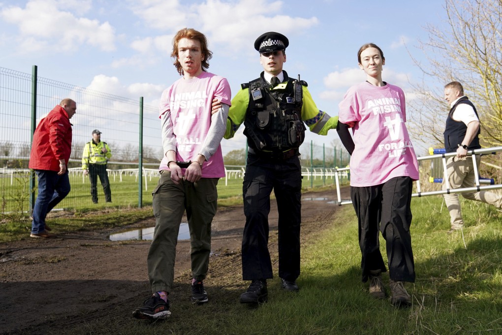 A police officer apprehends protesters attempting to get on to the course during day three of the Grand National at Aintree Racecourse in Liverpool, England, UK on Saturday. Photo: Tim Goode via AP