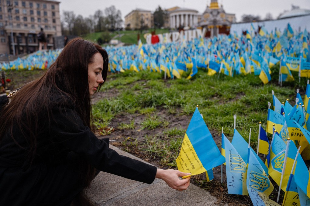 Ukrainian Olga Slyshyk places a flag in the memory of her killed husband at a makeshfit memorial. Photo: AFP